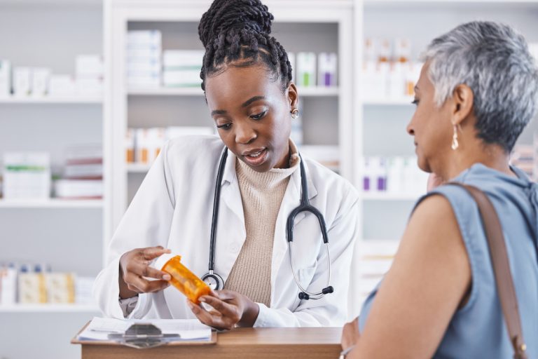 Young Black female pharmacist consulting senior female Latina client for prescription medication