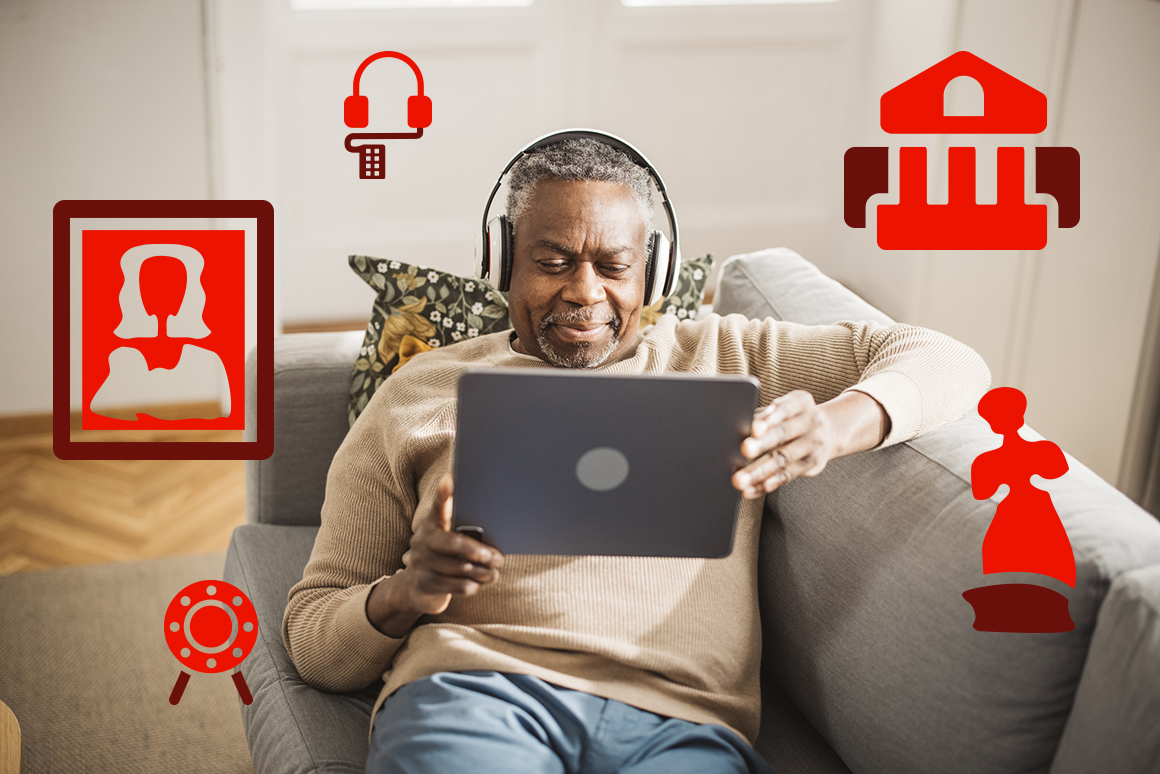 senior Black man wearing headphones watching virtual museum tour on laptop computer