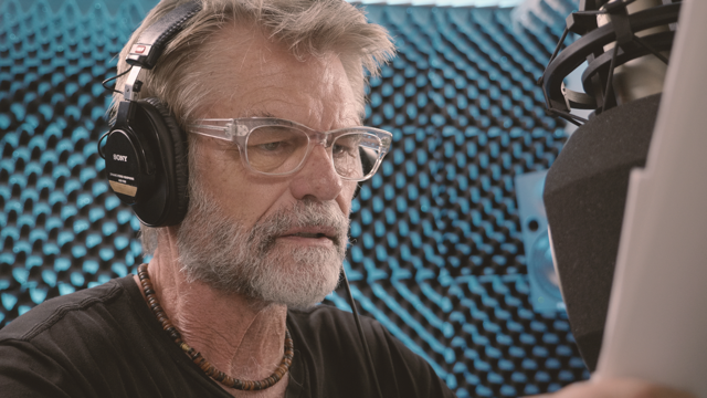 Photo of Actor Harry Hamlin wearing headphones and recording lines in a studio